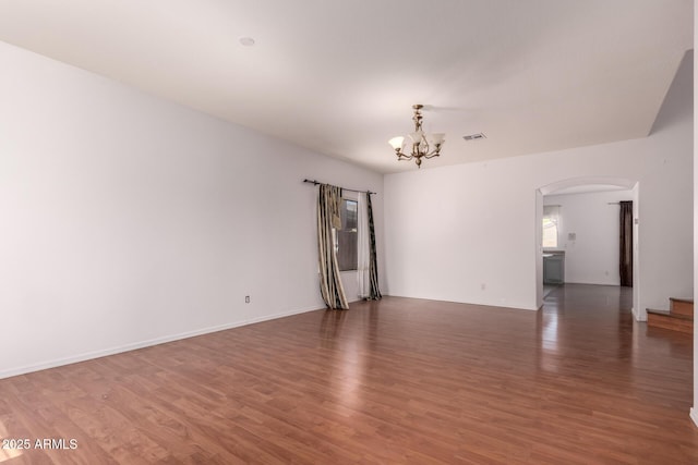 unfurnished room featuring visible vents, arched walkways, wood finished floors, and a notable chandelier