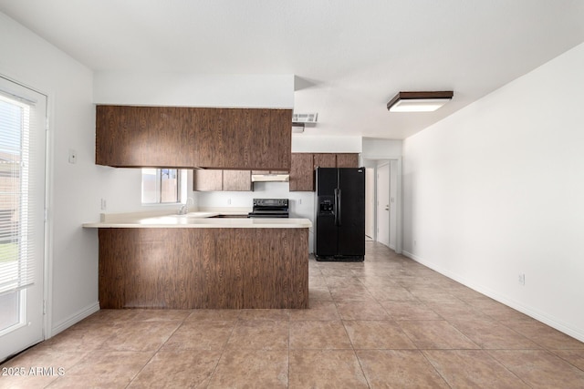 kitchen with a sink, a peninsula, light countertops, and black appliances