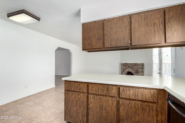 kitchen with stainless steel dishwasher, light tile patterned floors, arched walkways, light countertops, and baseboards