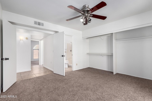 unfurnished bedroom with connected bathroom, a closet, tile patterned flooring, visible vents, and carpet floors