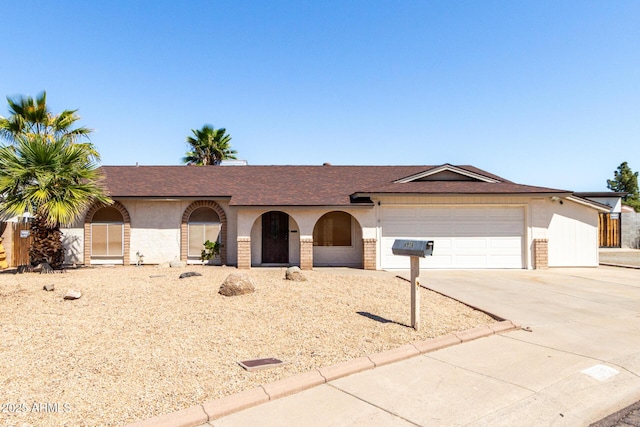 ranch-style home with brick siding, an attached garage, a shingled roof, and driveway