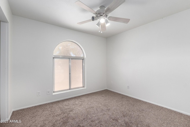carpeted spare room featuring baseboards and a ceiling fan