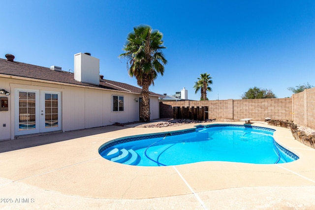view of swimming pool featuring a diving board, a patio area, a fenced backyard, french doors, and a fenced in pool