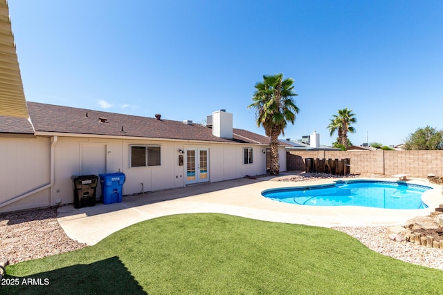 view of swimming pool featuring a fenced backyard, a lawn, a patio area, french doors, and a fenced in pool