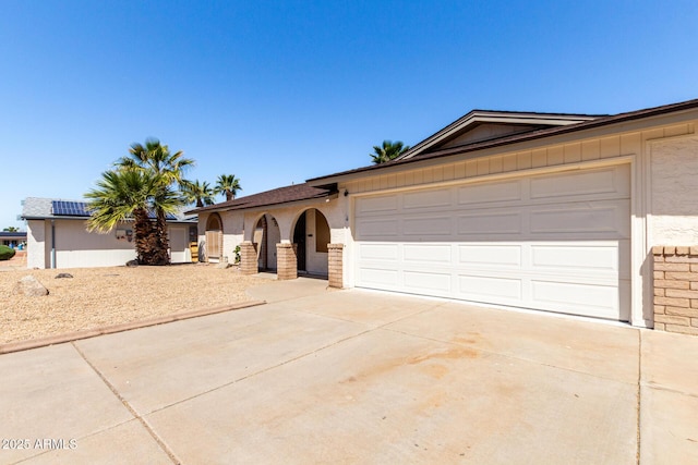ranch-style home with concrete driveway, a garage, and stucco siding