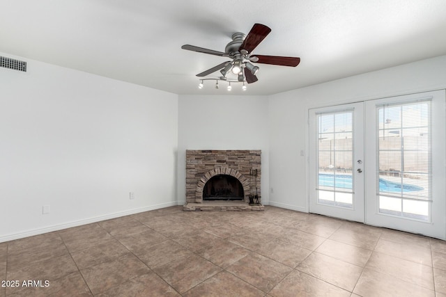 unfurnished living room featuring a ceiling fan, a stone fireplace, visible vents, tile patterned floors, and french doors