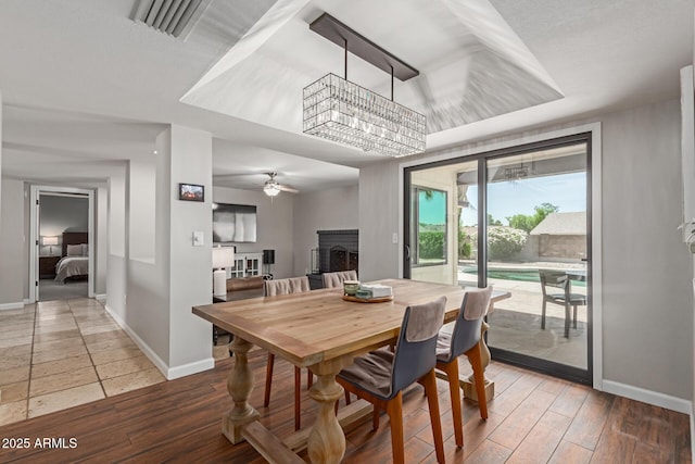 6417 E Kings Ave, Scottsdale, AZ 85254 - dining area with a fireplace, a tray ceiling, a ceiling fan, and wood finished floors