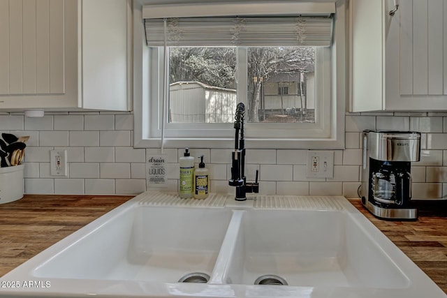 room details featuring light countertops, tasteful backsplash, a sink, and white cabinetry