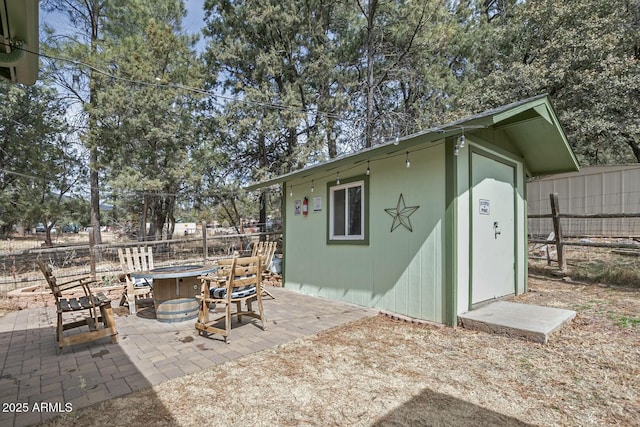 view of patio / terrace with an outbuilding, fence, and an outdoor fire pit