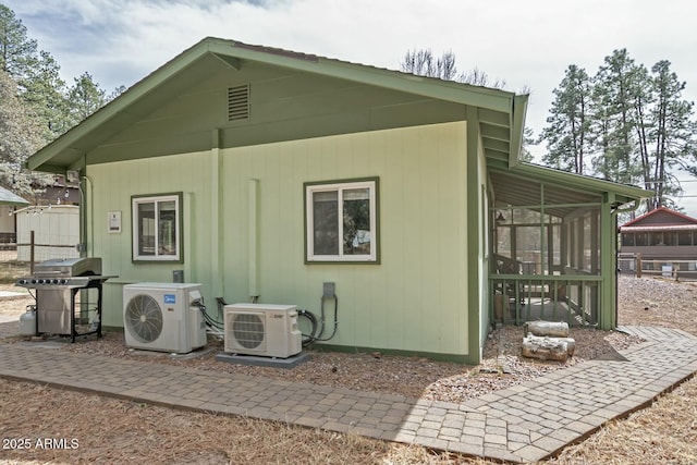 rear view of property with ac unit, fence, and a sunroom