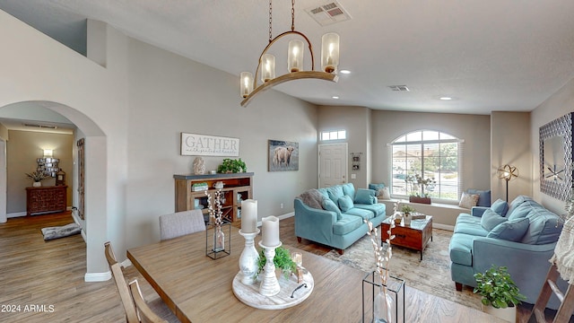 dining area featuring a notable chandelier, light hardwood / wood-style floors, and high vaulted ceiling