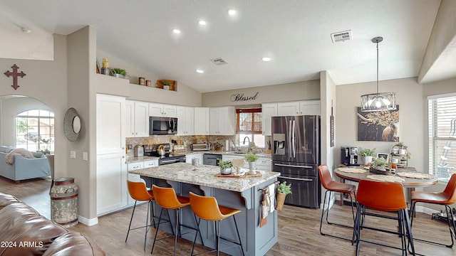 kitchen featuring a center island, white cabinets, sink, appliances with stainless steel finishes, and decorative light fixtures