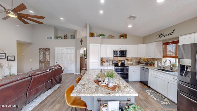 kitchen with a center island, white cabinets, sink, light wood-type flooring, and appliances with stainless steel finishes