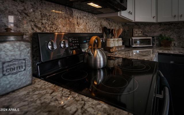 kitchen featuring white cabinets and black range