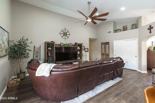 living room with ceiling fan, dark hardwood / wood-style flooring, and a towering ceiling