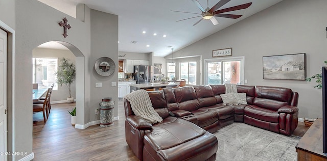 living room featuring ceiling fan, high vaulted ceiling, and light hardwood / wood-style floors