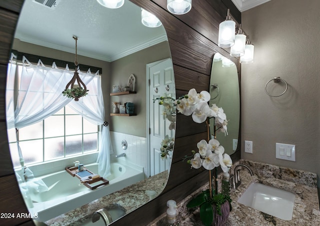 bathroom with a bathing tub, vanity, a healthy amount of sunlight, and ornamental molding