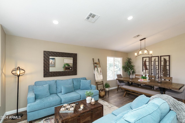 living room featuring hardwood / wood-style floors, lofted ceiling, and a notable chandelier