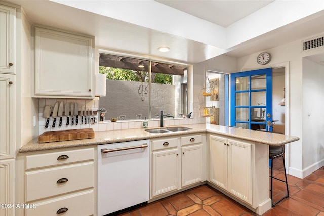 kitchen featuring kitchen peninsula, tasteful backsplash, sink, dishwasher, and a breakfast bar area