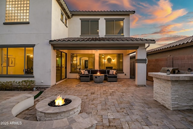 back of property featuring a patio, a fire pit, fence, exterior kitchen, and stucco siding