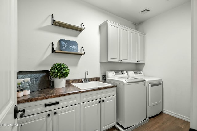 washroom featuring cabinet space, visible vents, dark wood-type flooring, washer and dryer, and a sink