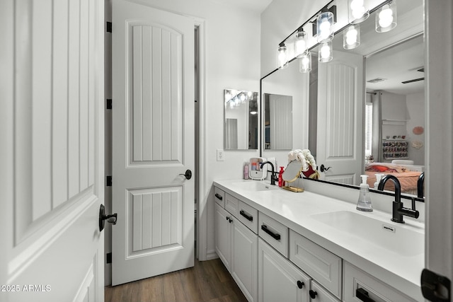 ensuite bathroom featuring double vanity, wood finished floors, a sink, and connected bathroom