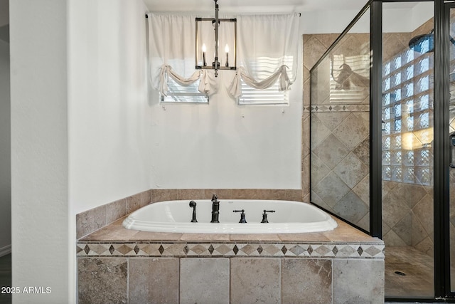 bathroom featuring a garden tub, an inviting chandelier, and a stall shower