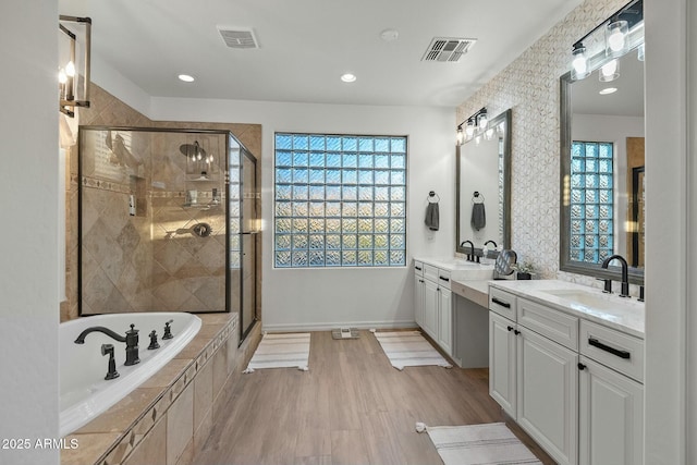 full bath featuring a garden tub, two vanities, a sink, visible vents, and a shower stall