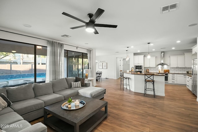 living room with ceiling fan, wood finished floors, visible vents, and recessed lighting