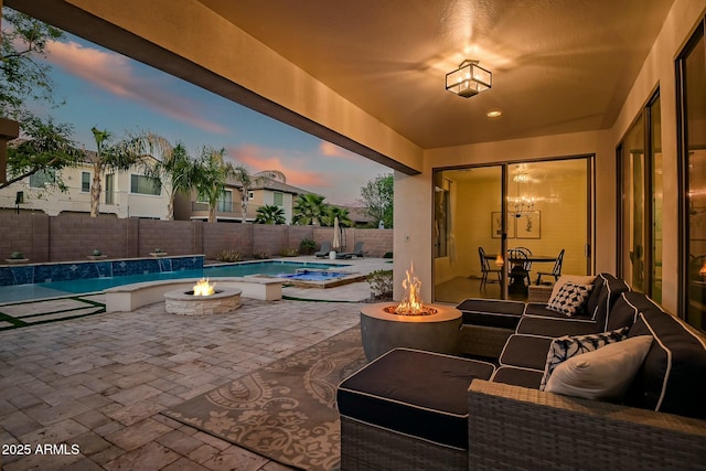 patio terrace at dusk with an outdoor fire pit, a fenced backyard, and a fenced in pool