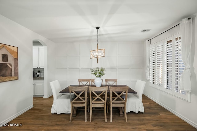 dining area featuring dark wood-type flooring, visible vents, a notable chandelier, and baseboards