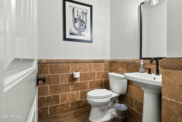 bathroom with a wainscoted wall, tile walls, toilet, and wood finished floors