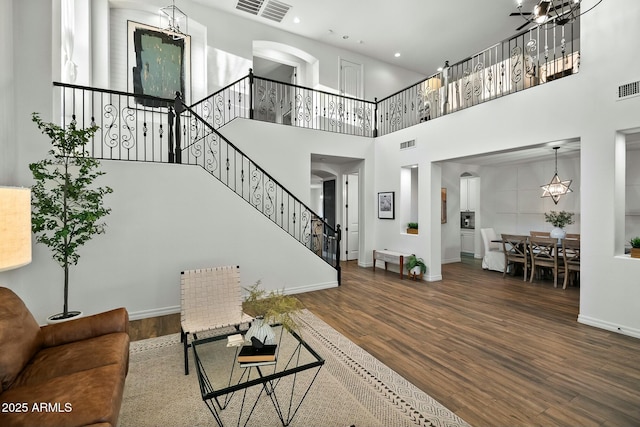 living room featuring stairs, wood finished floors, visible vents, and an inviting chandelier