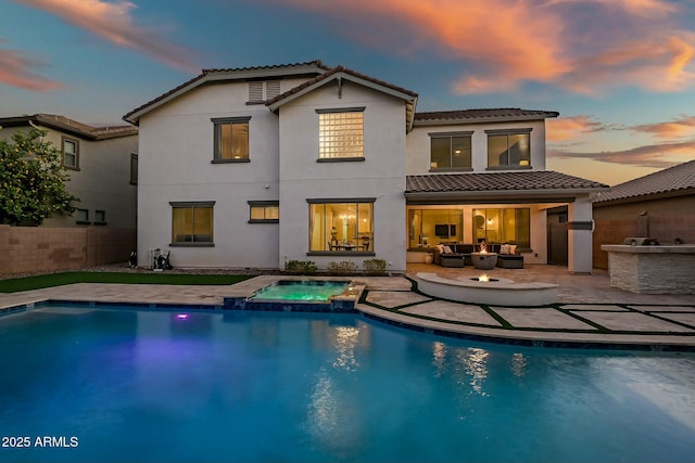 rear view of property with an outdoor kitchen, a patio, fence, a pool with connected hot tub, and an outdoor living space