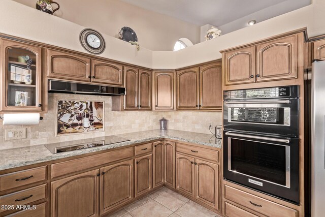 7648 W Mauna Loa Ln, Peoria, AZ 85381 - kitchen with black appliances, under cabinet range hood, light tile patterned floors, tasteful backsplash, and light stone countertops