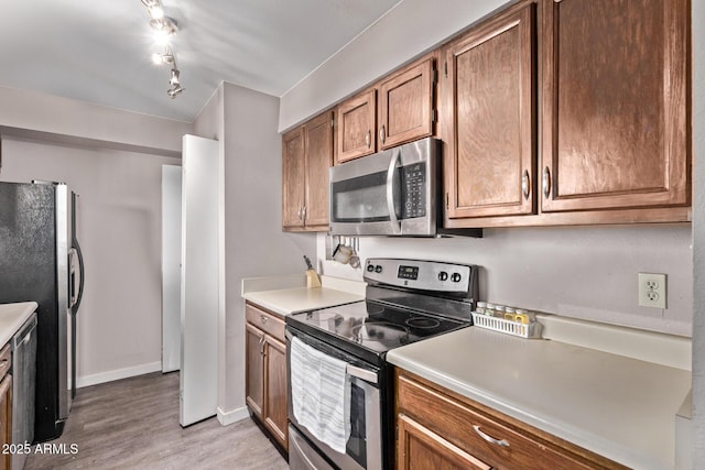7474 E Earll Dr Unit 311, Scottsdale, AZ 85251 - kitchen with stainless steel appliances, light wood-type flooring, baseboards, light countertops, and brown cabinetry