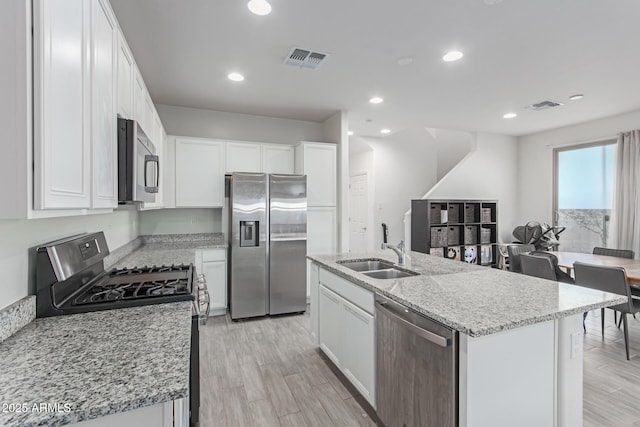 3714 S 58th Dr, Phoenix, AZ 85043 - kitchen with appliances with stainless steel finishes, a sink, white cabinets, light stone counters, and a kitchen island with sink
