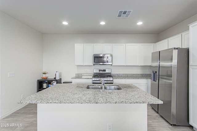 3714 S 58th Dr, Phoenix, AZ 85043 - kitchen featuring stainless steel appliances, a sink, white cabinetry, light stone countertops, and an island with sink