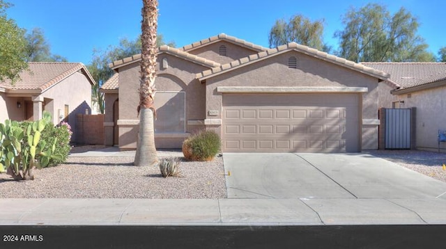 view of front facade with a tiled roof, stucco siding, an attached garage, and driveway