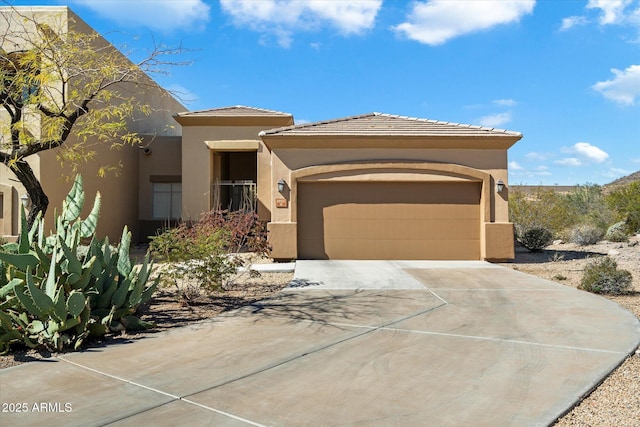 view of front facade featuring concrete driveway, a tile roof, an attached garage, and stucco siding