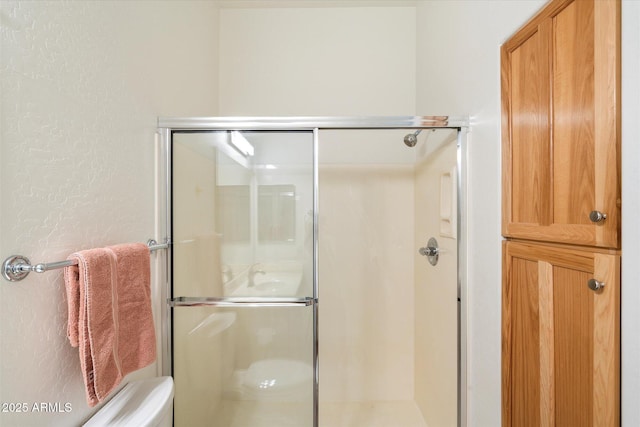 full bath featuring a shower stall and a textured wall