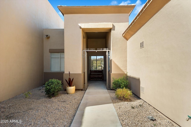 entrance to property with visible vents and stucco siding