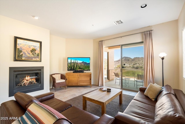 living room featuring a glass covered fireplace, visible vents, and recessed lighting