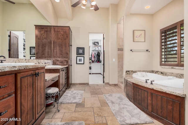 21615 E Pegasus Pkwy, Queen Creek, AZ 85142 - full bath featuring stone tile floors, a ceiling fan, vanity, a walk in closet, and a garden tub
