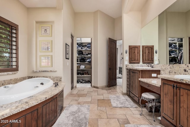 21615 E Pegasus Pkwy, Queen Creek, AZ 85142 - full bathroom featuring a walk in closet, a garden tub, stone tile floors, and vanity