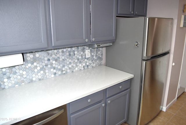 kitchen featuring backsplash, stainless steel fridge, gray cabinets, and light tile patterned floors