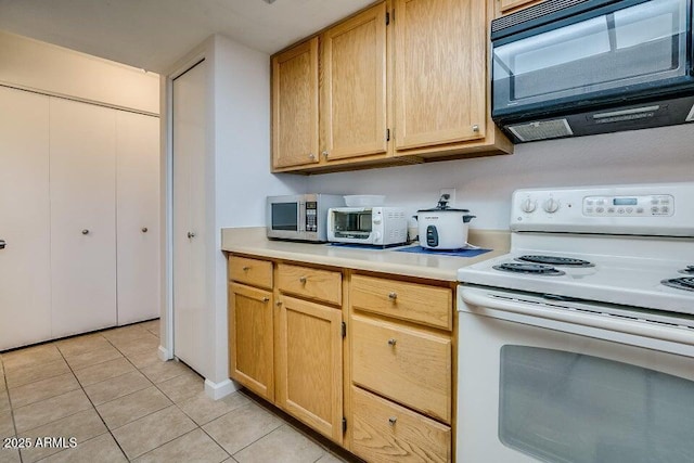 kitchen featuring electric stove, light brown cabinets, and light tile patterned floors