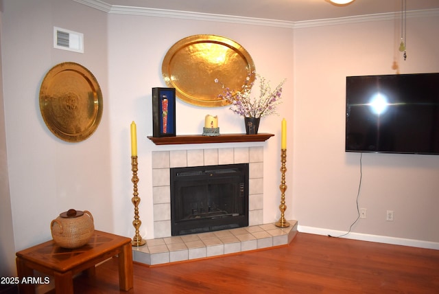 living room featuring a tiled fireplace, hardwood / wood-style floors, and crown molding