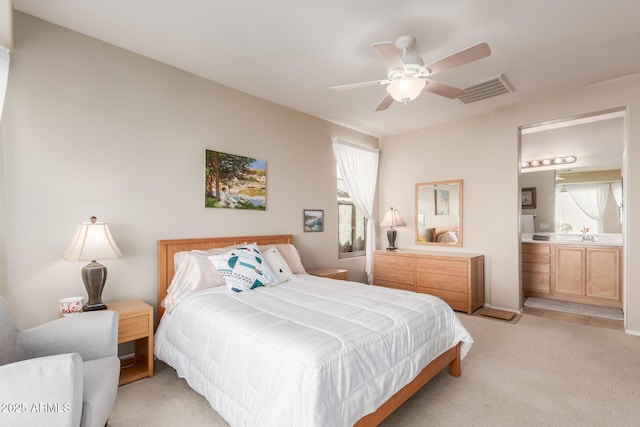 bedroom featuring connected bathroom, light colored carpet, and ceiling fan