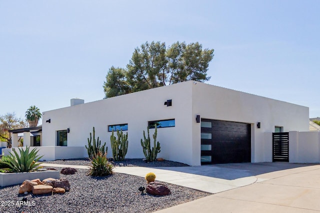 contemporary house featuring driveway, an attached garage, fence, and stucco siding